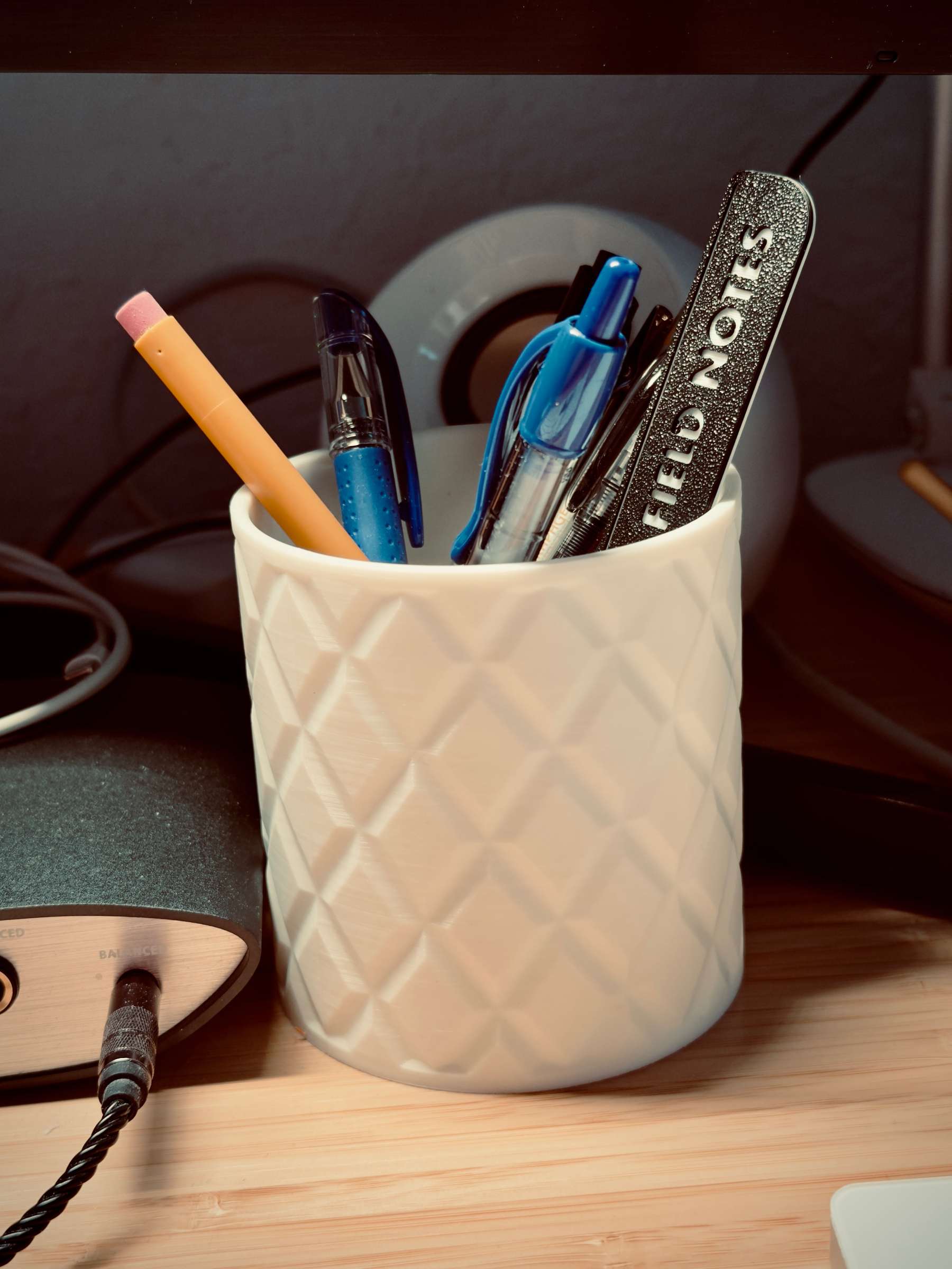 A white 3-D printed cup to hold my pens, pencils, straight edge, etc. The outside walls of the cup have a texture to it, akin to a brick wall of sorts. The print came out, very smooth all around except for the textured parts which was intentional. ￼
